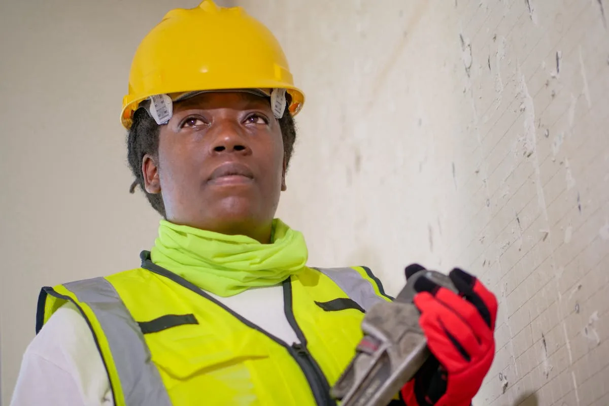 Technicien de maintenance tenant une clé à tuyau sur chantier de plomberie — vanne d'arrêt automatique et prévention des dégâts des eaux
